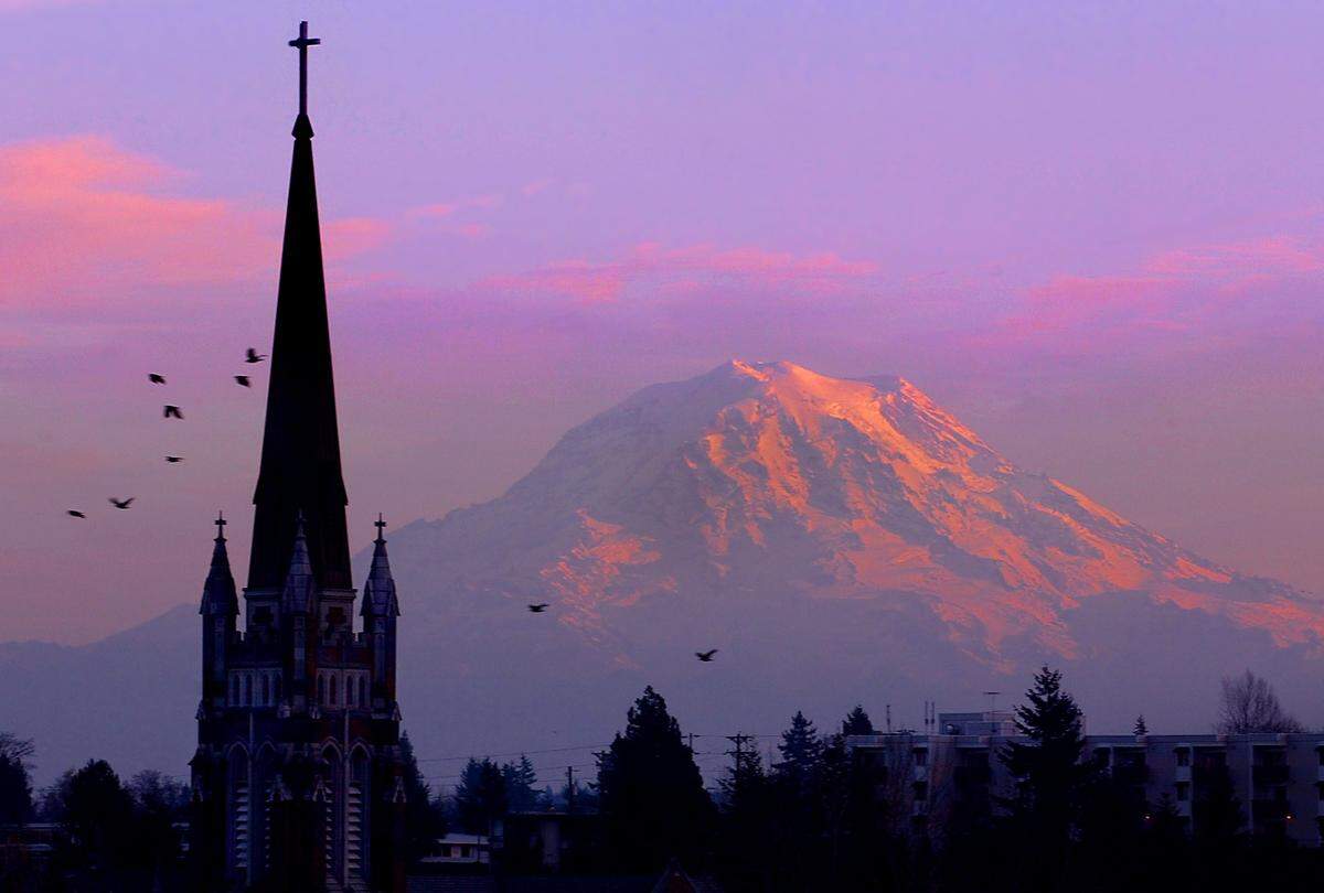 In this Dec. 2002 file photo, the iconic steeple of Holy Rosary Church, easily seen from Interstate 5, is silhouetted as sunset colors Mount Rainier.