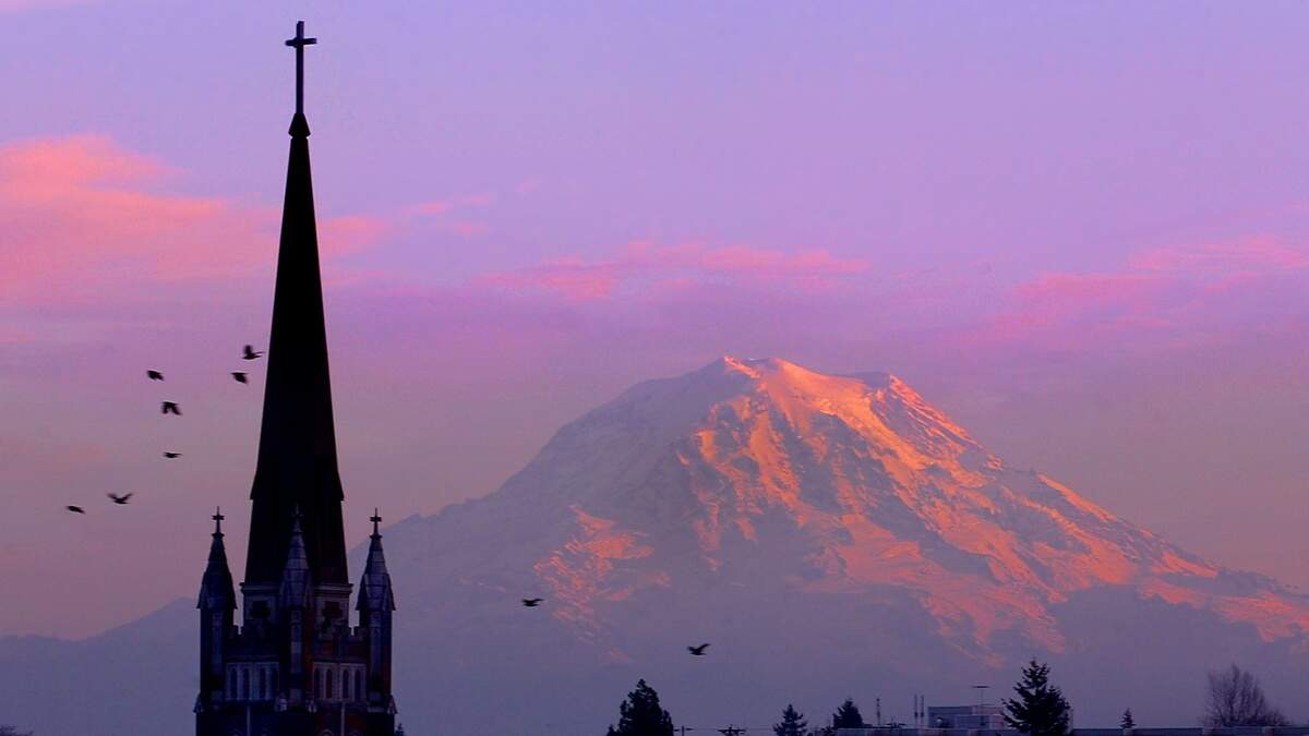 In this Dec. 2002 file photo, the iconic steeple of Holy Rosary Church, easily seen from Interstate 5, is silhouetted as sunset colors Mount Rainier.