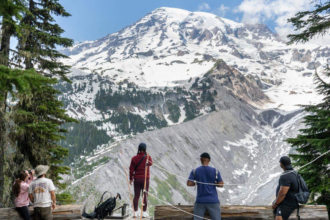 People look out at Mount Rainier from a viewpoint along the Nisqually Vista Trail on Friday, June 6, 2025, at Mount Rainier National Park. The Nisqually Glacier and the start of the Nisqually River are visible from this point, as well as other active and inactive glaciers on the mountain.