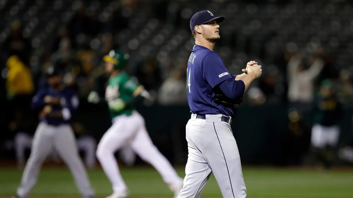 Seattle Mariners’ Connor Sadzeck, right, waits for Oakland Athletics’ Stephen Piscotty to run the bases on a home run during the eighth inning of a baseball game Friday, May 24, 2019, in Oakland, Calif.