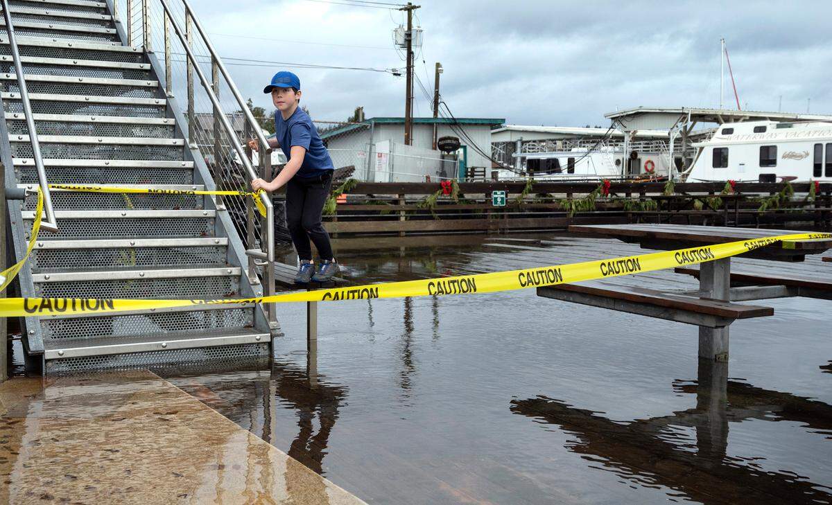 Frankie Hall, 9, of Gig Harbor, negotiates the high-tide floodwaters at the Jerisich Dock along the waterfront in Gig Harbor, Washington, on Tuesday, Dec. 27, 2022.