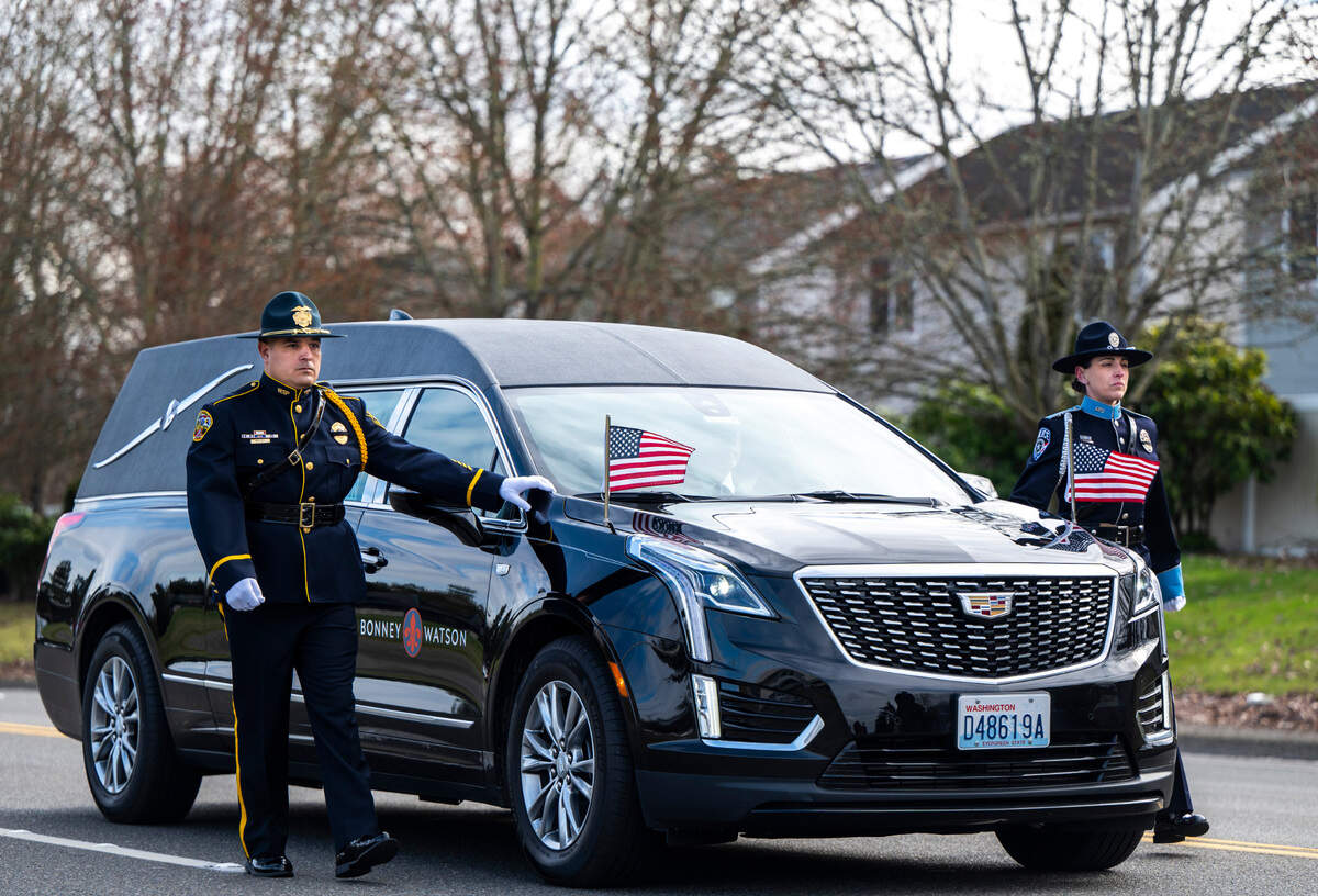 Officers walk alongside a hearse carrying Jay Miller, a former corrections officer at the Washington Corrections Center For Women, during a procession in his honor on the way to his memorial service at the Church for All Nations in Parkland, Wash. Feb. 22, 2023. Miller worked for the Department of Corrections for 30 years and passed away at the age of 56, from COVID-19 complications.