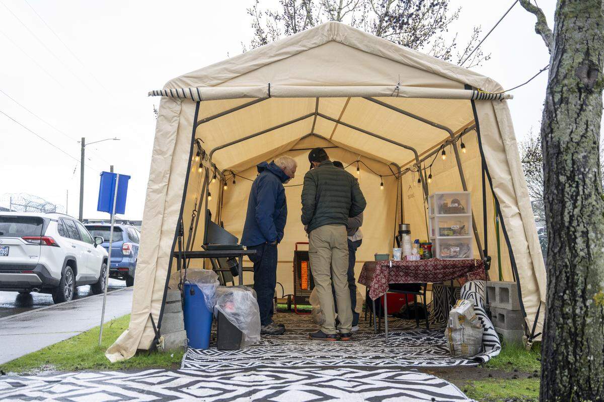 Volunteers Dick Kuehn, left, and Chris Hallam, front, speak with a recently released detainee at the welcome center run by Advocates for Immigrants in Detention Northwest on Friday, March 20, 2026, outside of the Northwest ICE Processing Center in Tacoma, Wash.