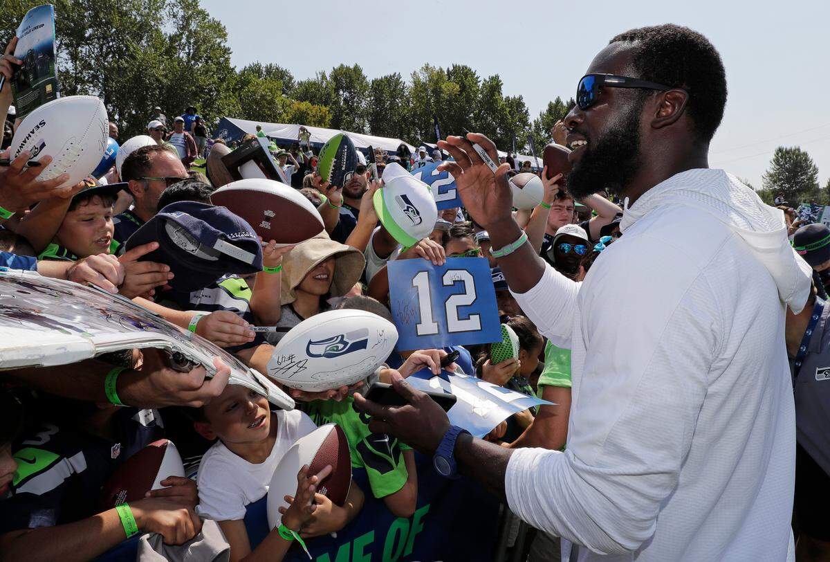 Retired Seahawks strong safety Kam Chancellor signs autographs for fans as he visits Seattle’s training camp in Renton last August. The team announced its 2019 training camp begins with a first practice on July 25.