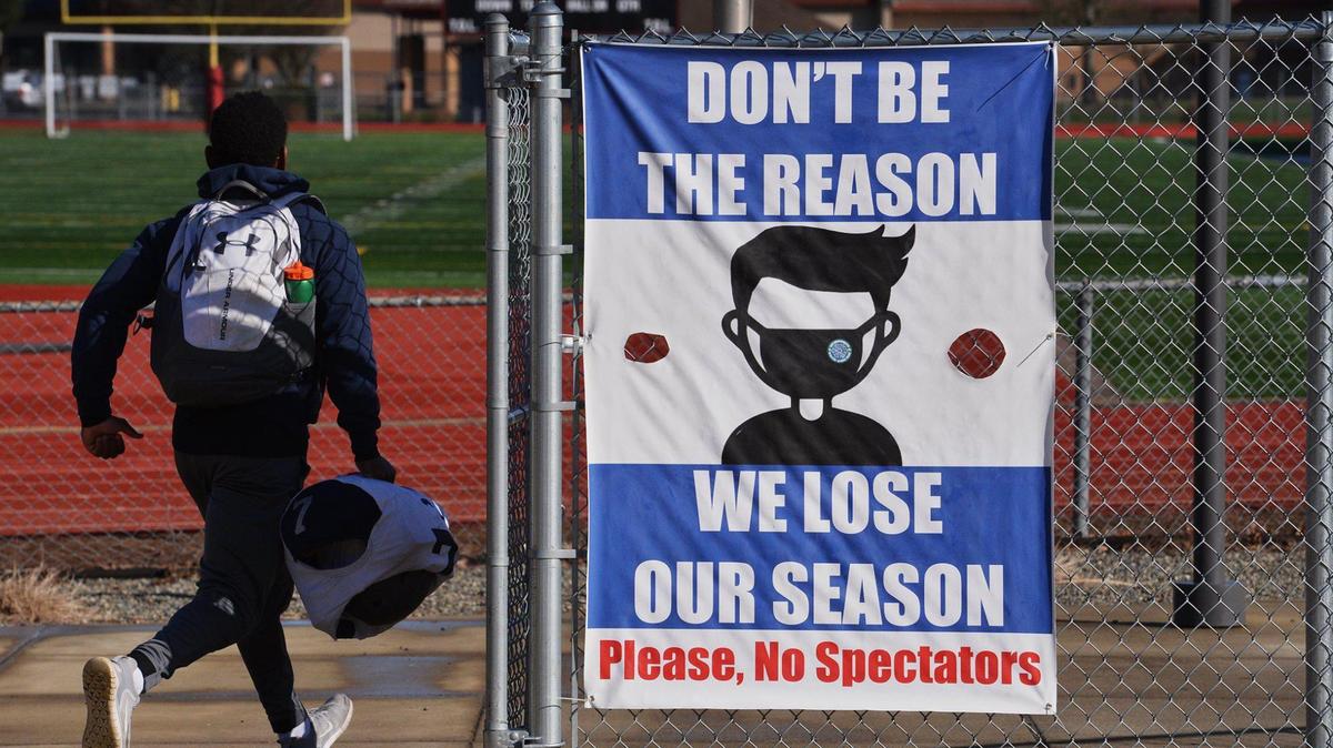 Heading into South Sound Stadium for a Tuesday afternoon practice a River Ridge High School, football player passes a sign reminding fans about pandemic restrictions. Photo taken Feb. 23,2021