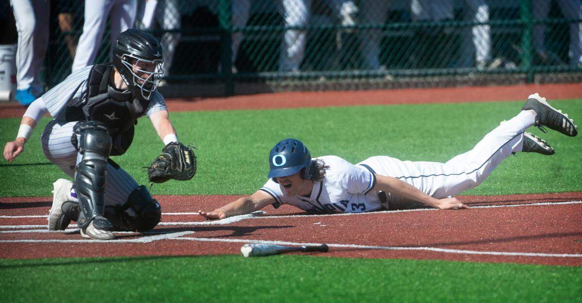 Olympia baserunner Evan Nicol slides home in front of the tag attempt by Issaquah catcher Kallen Rundle during the Bears 6-0 victory over Issaquah in the quarterfinal round of the 4A state baseball tournament at the Regional Athletic Complex in Lacey, Washington, on Saturday, May 22, 2022.
