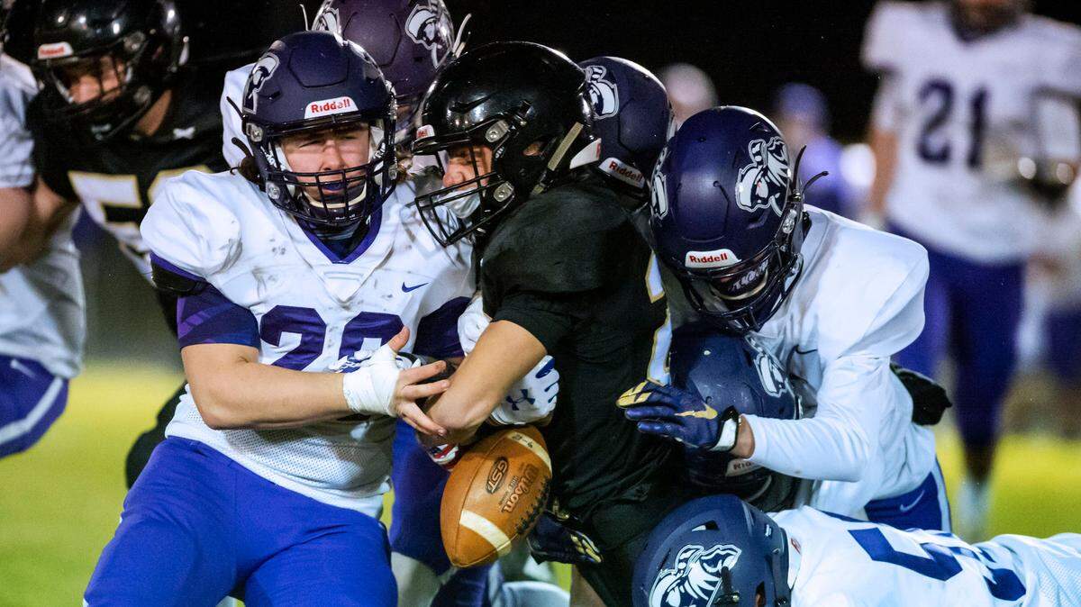 Meridian running back Trey Naidu (20) gets the ball knocked loose while being stopped by Nooksack defender Jeff Boykin (20), left, and other defenders at the line of scrimmage during the first quarter on Friday evening Feb. 27, 2021, in Laurel, Wash. The ruling on the field was a dead ball as the carrier’s knee was on the ground. Meridian went on to defeat Nooksack 17 to 10. (Paul Conrad for The Bellingham Herald)