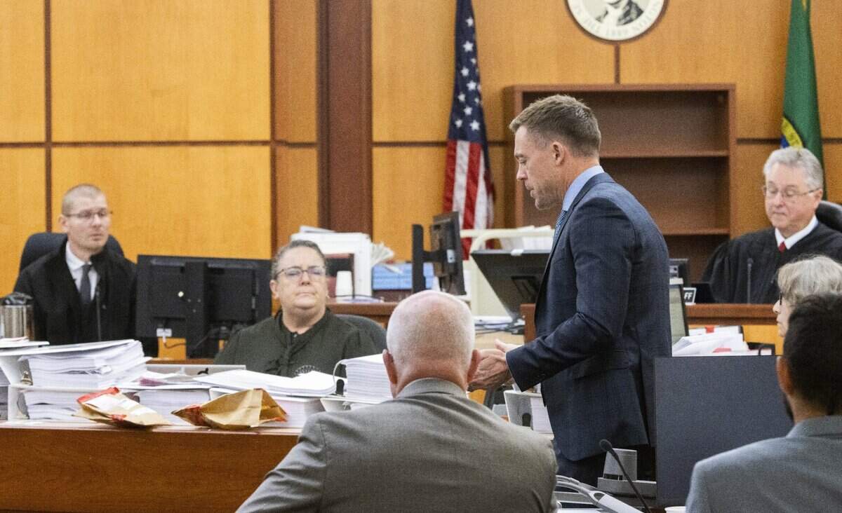 Defense attorney Casey Arbenz, standing, cross-examines Jacob Atzet, left, a death investigator for Pierce County, in Pierce County Superior Court, Wednesday, Oct. 12, 2023.