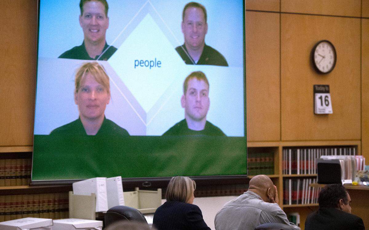 Defendant Dorcus Allen covers his face as the four Lakewood police officers killed in 2009 by Maurice Clemmons are shown in Pierce County Superior Court in Tacoma, Washington, on Thursday, Feb. 16, 2023, during closing arguments in Allen’s third trial for first-degree murder charges.