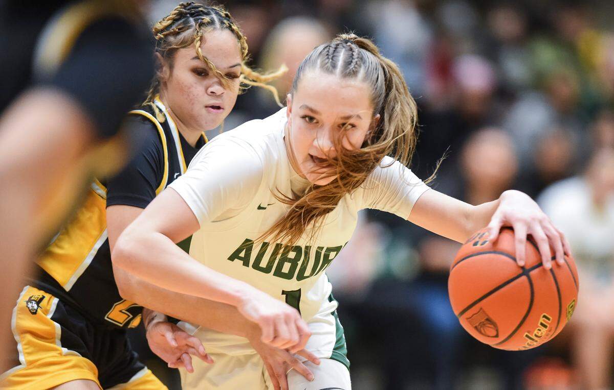 Auburn’s Avery Hansen (1) tries to cut around Lincoln’s Jaleigha Robinson (23) during the opening round of the 3A District 3/4 basketball tournament at Auburn High School on Friday, Feb. 9, 2024, in Auburn, Washington.