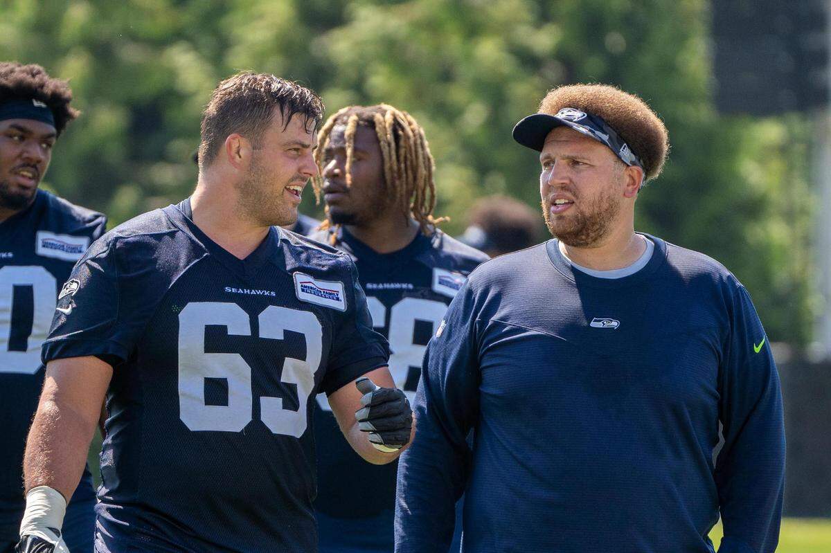 Seattle Seahawks center Austin Blythe talks with offensive line coach Andy Dickerson as they walk off the field after the second day of Seahawks training camp at the Virginia Mason Athletic Center in Renton, Wash. on July 28, 2022.