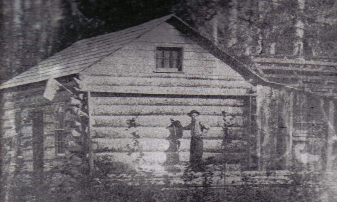 Job Carr, the first permanent non-native resident of Tacoma, poses in front of his cabin in a photo taken by his son in 1866.
