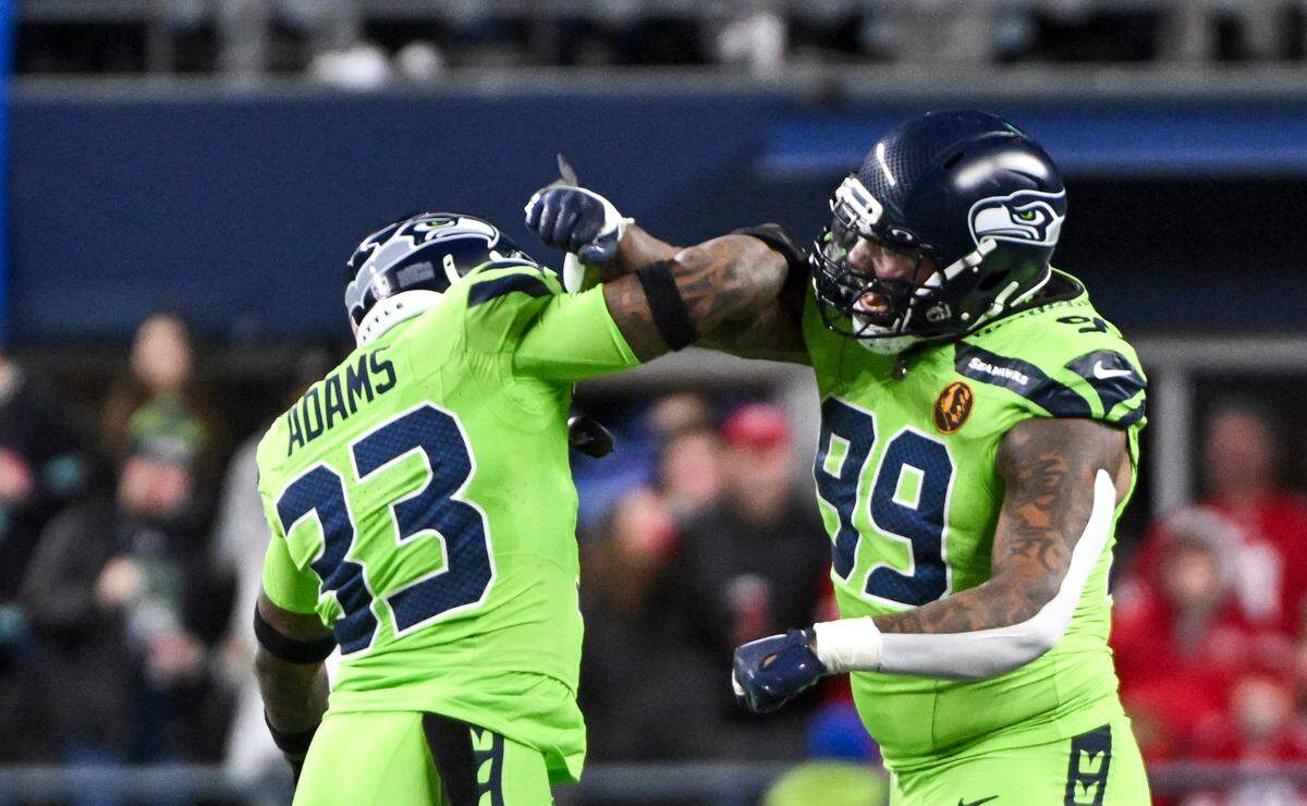 Seattle Seahawks safety Jamal Adams (33) and defensive end Leonard Williams (99) celebrate a hit on San Francisco 49ers quarterback Brock Purdy (13) during the first quarter of the game at Lumen Field, Thursday, Nov. 23, 2023, in Seattle, Wash.