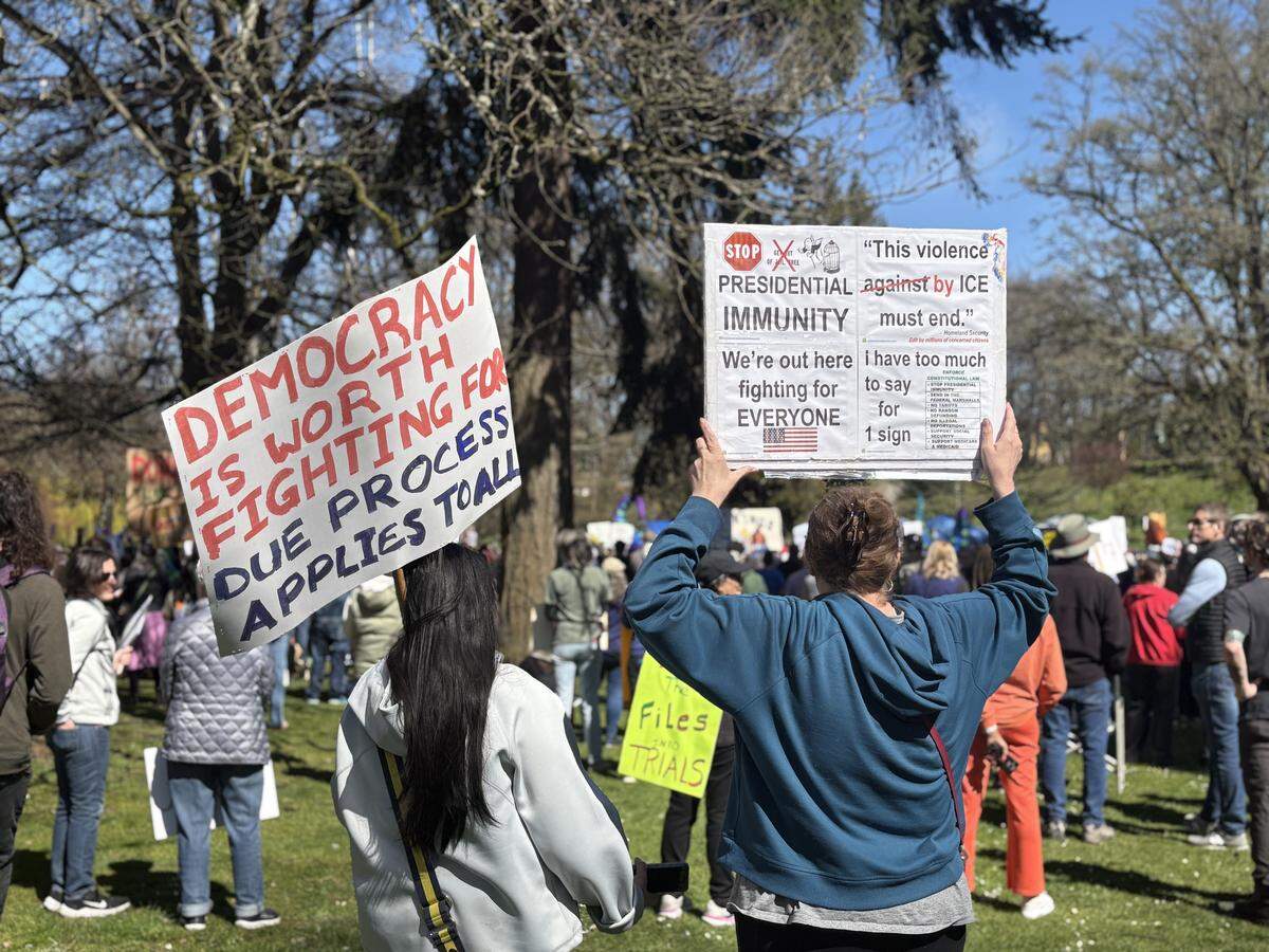 Protestors hold homemade signs at Wright Park’s “No Kings” rally on Saturday, March 28, 2026.