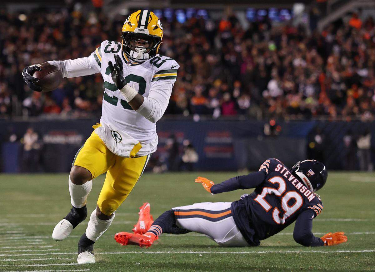 CHICAGO, ILLINOIS - DECEMBER 20: Emanuel Wilson #23 of the Green Bay Packers carries the ball past Tyrique Stevenson #29 of the Chicago Bears during the third quarter at Soldier Field on December 20, 2025 in Chicago, Illinois. (Photo by Michael Reaves/Getty Images)
