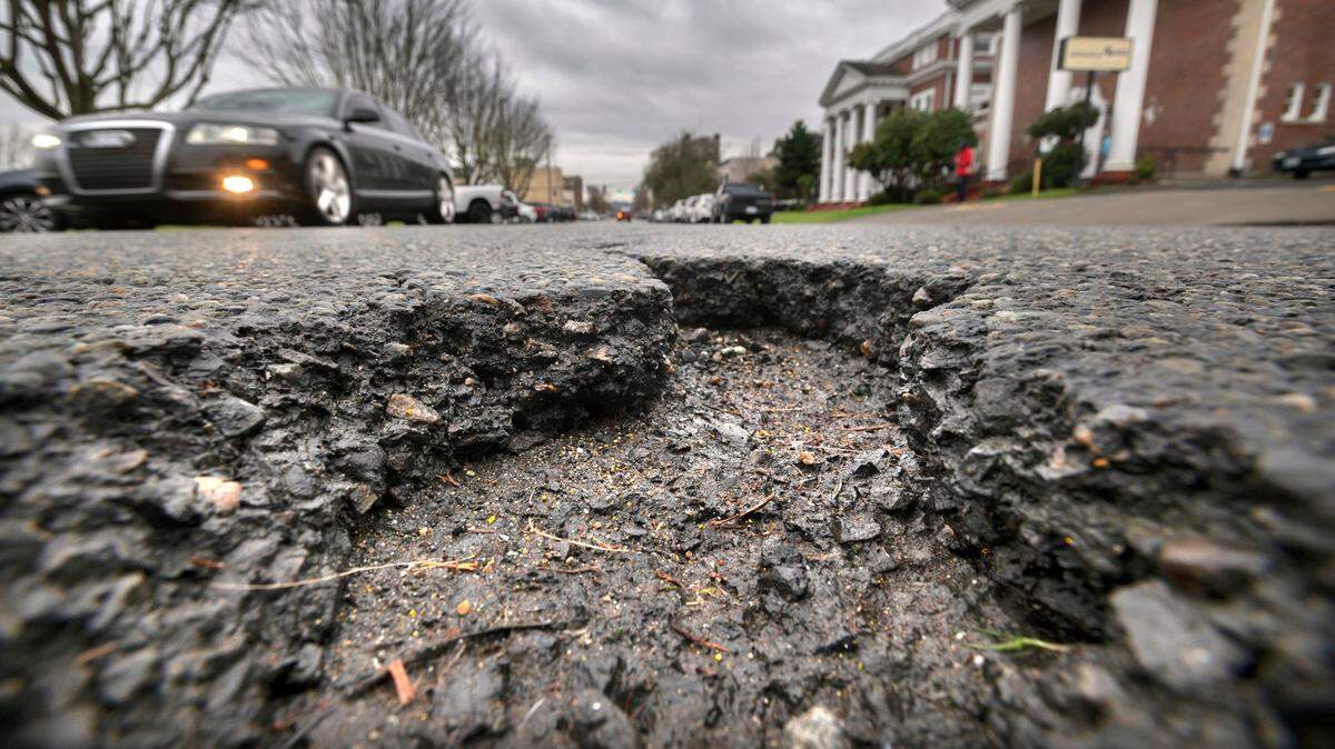 Traffic rolls past deep pothole on Tacoma Avenue South in Tacoma on Jan. 5, 2022.