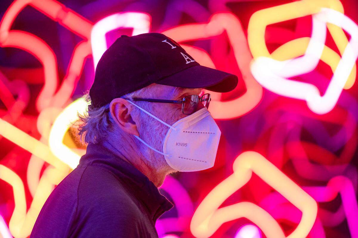 Steve Kocsis, of Juneau, Alaska, stands. In front of Dani Kaes’ neon installation named “Clyde’s Bargain Bin Boots (For Dogs, Too)” as he strolls through the “GATHER: 27 Years of Hilltop Artists” at the Tacoma Art Museum on Wednesday, March 30, 2022, in Tacoma, Wash.