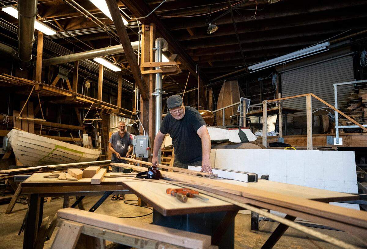 Jonathan Cunningham, right, and Anthony “Mike” Vlahovich, left, cut boards for a Croatian fishing boat that is being built as part of “The Batana Project” at the Gig Harbor Boat Shop in Gig Harbor, Wash. on Wednesday, July 20, 2022. Once the boat is complete, the boat shop will host an event to reveal it Sept. 3.