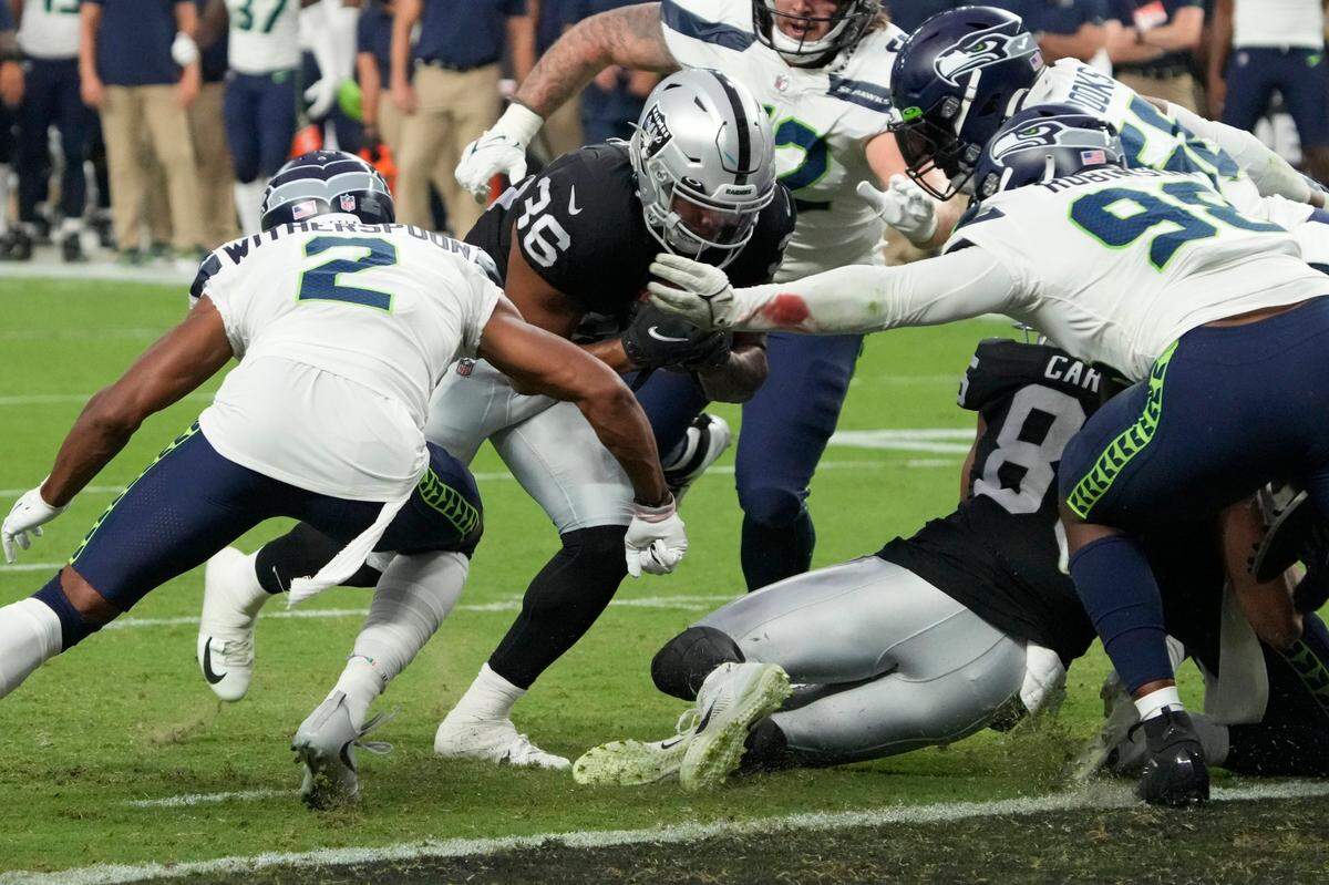Las Vegas Raiders running back Trey Ragas (36) scores a touchdown against Seattle Seahawks cornerback Ahkello Witherspoon (2) and Seattle Seahawks defensive end Alton Robinson (98) during the first half of an NFL preseason football game, Saturday, Aug. 14, 2021, in Las Vegas. (AP Photo/Rick Scuteri)