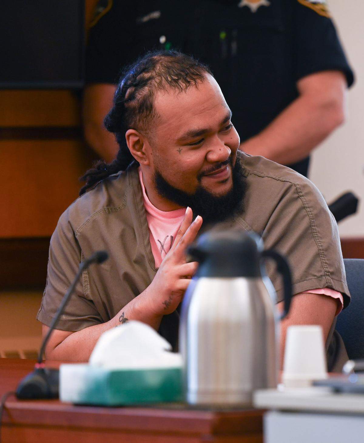 Augustino Maile flashes a smile and throws up a peace sign to family members in the gallery ahead of his sentencing for first-degree manslaughter in the death of 2-year-old Sarai Brooks and two counts of second-degree assault of two other children, in Pierce County Superior Court on Thursday, July 11, 2024 in Tacoma.