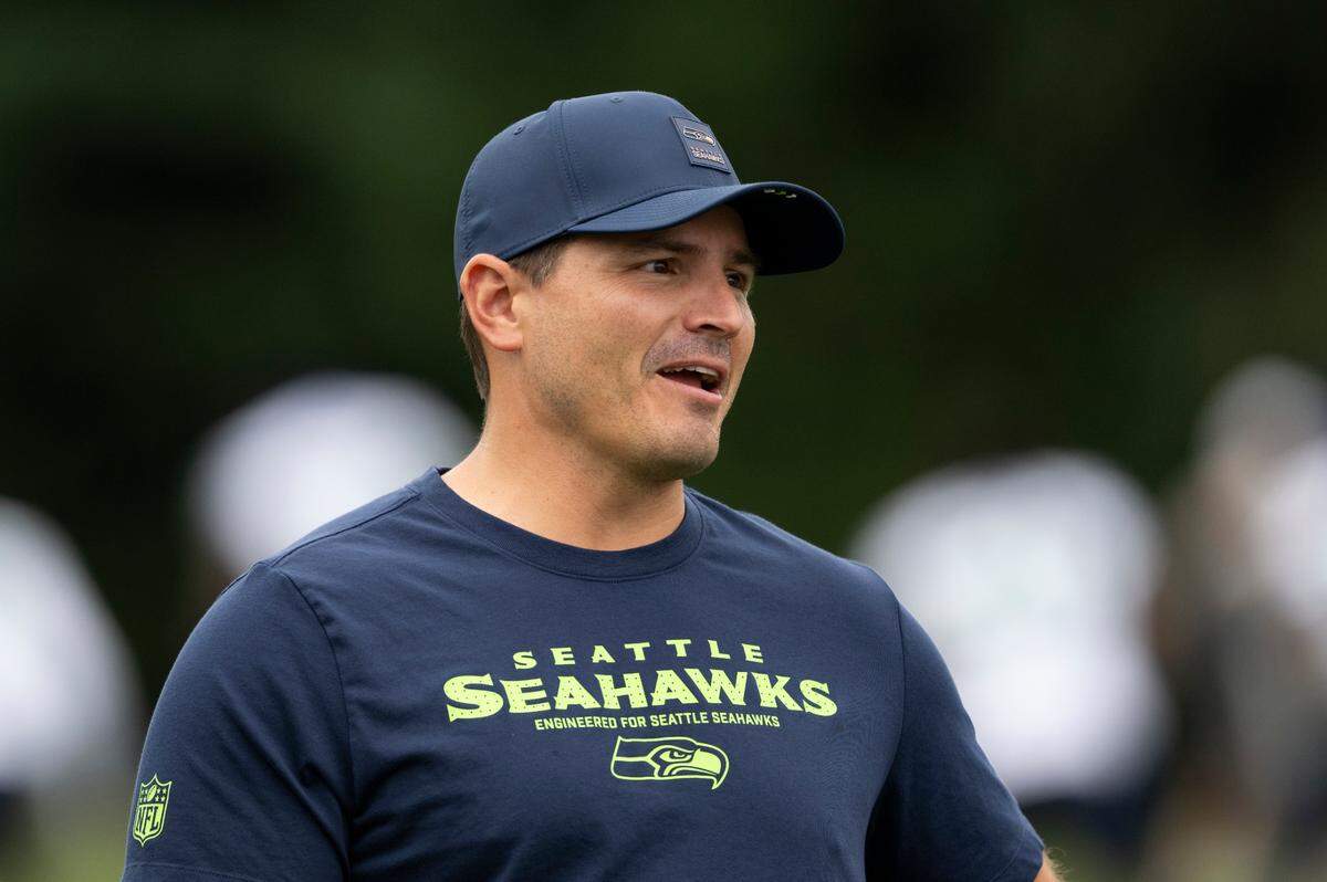 Seattle Seahawks head coach Mike Macdonald talks with players as they warm up during training camp at Virginia Mason Athletic Center on Friday, July 25, 2025, in Renton.