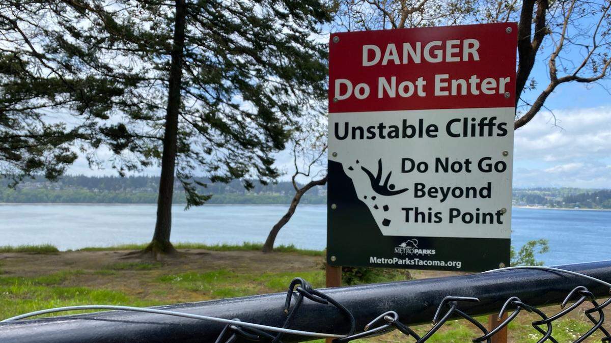 A sign and fencing is meant is to keep visitors away from dangerous cliffs along the Five Mile Drive at Point Defiance Park in Tacoma. The drive closed to traffic in May.