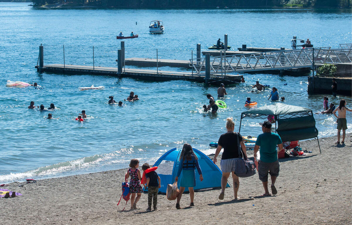 A family searches for the perfect spot on the beach at American Lake Park in Lakewood Saturday, July 2, 2021.