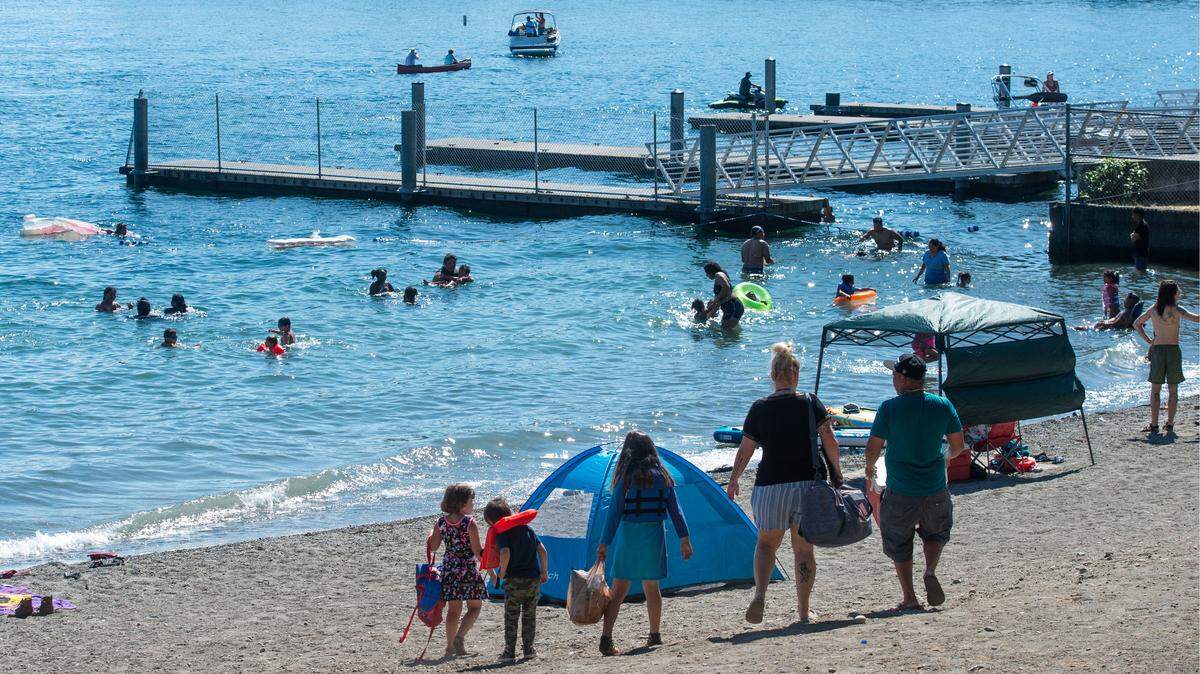 A family searches for the perfect spot on the beach at American Lake Park in Lakewood on July 2, 2021.