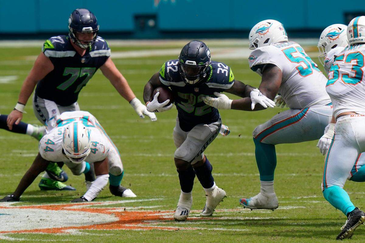Seattle Seahawks running back Chris Carson (32) avoids a tackle by Miami Dolphins outside linebacker Jerome Baker (55), during the first half of an NFL football game, Sunday, Oct. 4, 2020, in Miami Gardens, Fla. (AP Photo/Lynne Sladky)