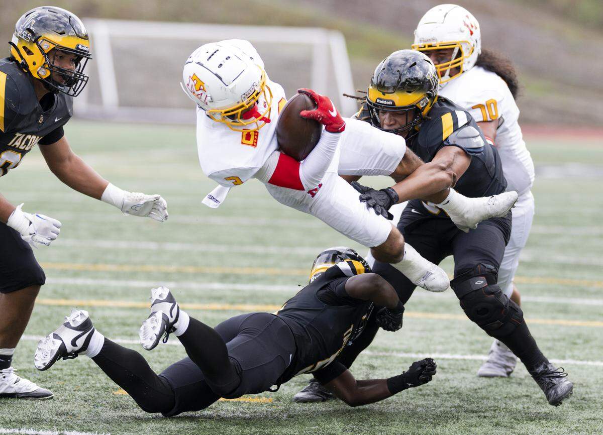 Mount Tahoma running back Felix Diaz (3) gets airborne on a tackle from Lincoln defensive end Kaivone Cooks (32) and safety Immanuel Jordan (5) during the second half of the game at Lincoln High School, on Saturday, Oct. 4, 2025, in Tacoma, Wash.