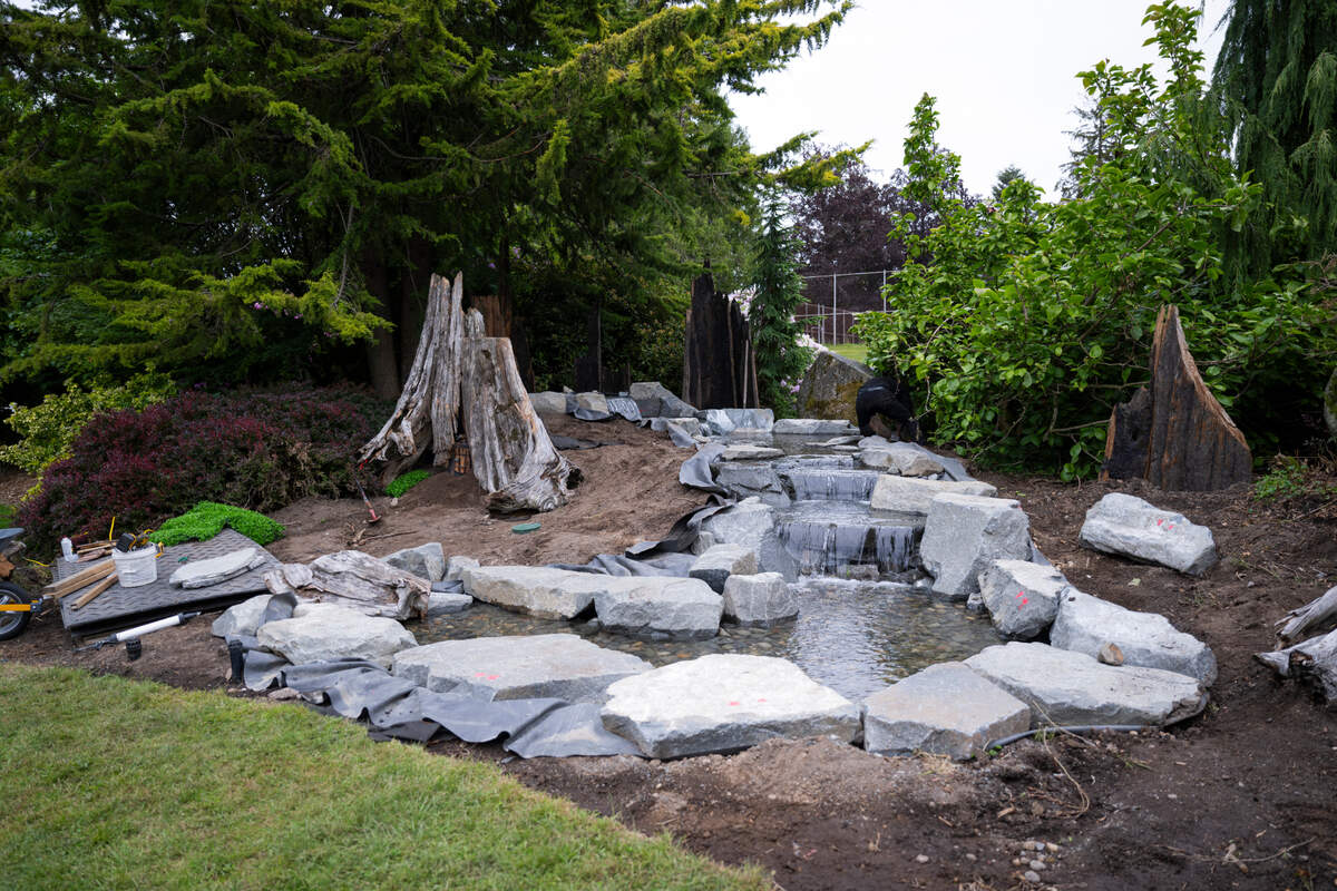 Award-winning garden designer Landen Moore, owner of Nature Perfect Landscape and Design, works on the water feature of the fairy garden at Point Defiance Park, on Thursday, May 23, 2024, in Tacoma.