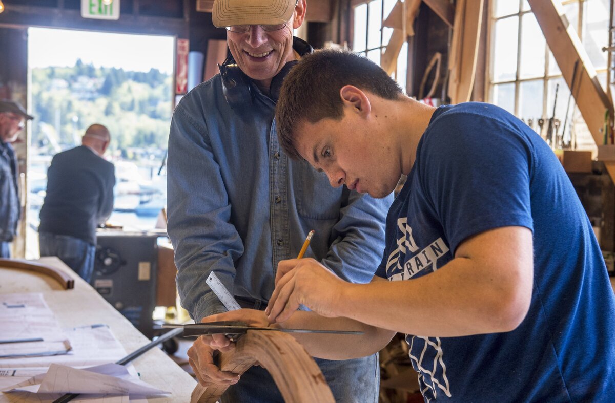 Boatwright Tom Regan (center) teaches Henderson High School sophomore Josh Jensen how to build a wooden boat at Gig Harbor BoatShop April 25.