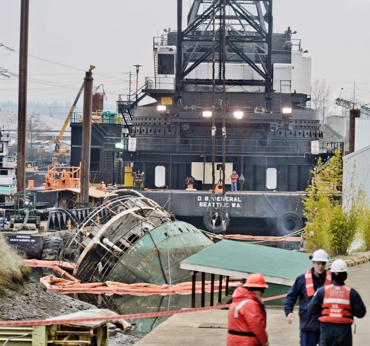 A massive crane sitting on a barge looms over the derelict ship Helena Star in Tacoma’s Hylebos Waterway, Dec. 2, 2013. The owner of the vessel pleaded guilty to abandoning the derelict vessel and discharging pollution into state waters.