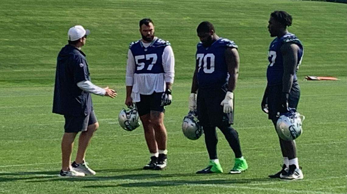 New Seahawks starting center Connor Williams (57) talks with offensive line coach Scott Huff (left), starting left guard Laken Tomlinson (70) and starting left tackle Charles Cross (right) during extra work following practice Thursday, Sept. 5, 2024, at the Virginia Mason Athletic Center in Renton.