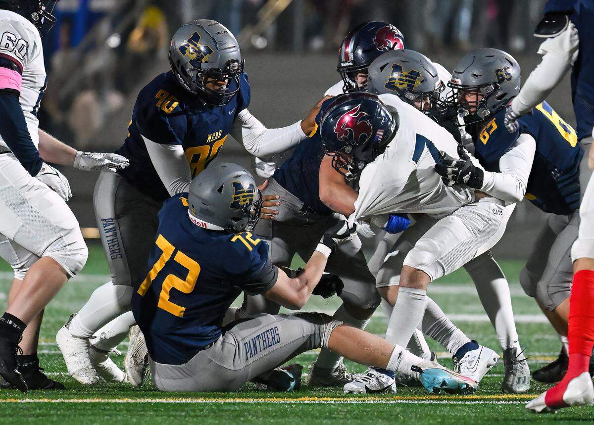 Mt. Spokane’s Matteo Saccomanno is pulled to the turf by Mead defensive lineman Cooper Daines (72) during a  Battle of the Bell high school football game, Friday, Oct. 27, 2023, at Union Stadium in Mead.