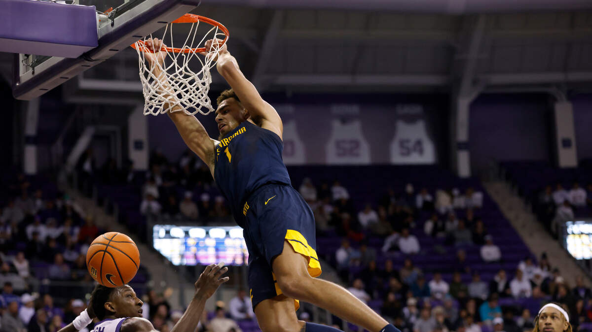 West Virginia forward Emmitt Matthews Jr. (1) hangs on the rim after dunking as TCU’s Damion Baugh (10) and Xavier Cork, right, look on in the second half of an NCAA college basketball game, Tuesday, Jan. 31, 2023, in Fort Worth, Texas. (AP Photo/Ron Jenkins)