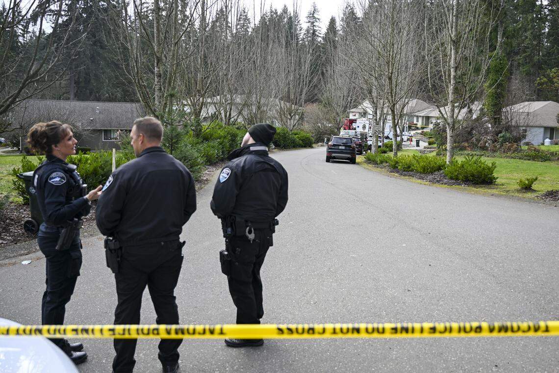 Personnel from the Pierce County Sheriff’s Office stand near crime scene tape as the investigation into five people fatally stabbed and the suspect shot dead by a deputy near Purdy, on Tuesday, Feb. 24, 2026.
