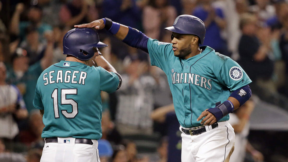 Seattle Mariners’ Robinson Cano, right, gives Kyle Seager a pat after scoring against the Los Angeles Angels during the sixth inning of a baseball game Friday, Aug. 11, 2017, in Seattle. (AP Photo/Elaine Thompson)