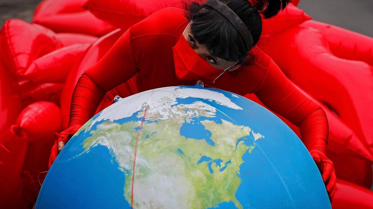 Artist and environmental activist Kong Ning poses on a globe Thursday in support on Earth Day in Beijing, China