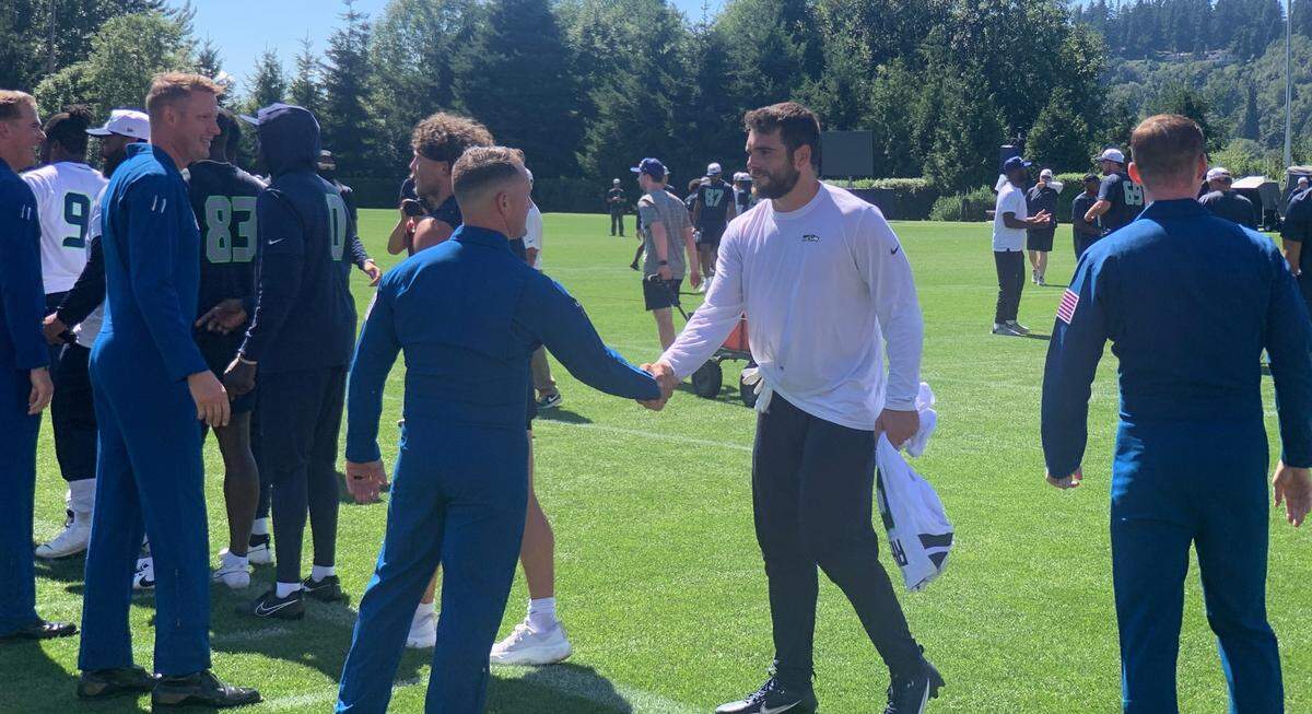 Linebacker and West Point graduate Jon Rhattigan (white long-sleeved) shakes the hand of a U.S. Navy Blue Angels pilot during the pilots visit to the seventh practice of Seahawks training camp July 31, 2024, at the Virginia Mason Athletic Center in Renton.