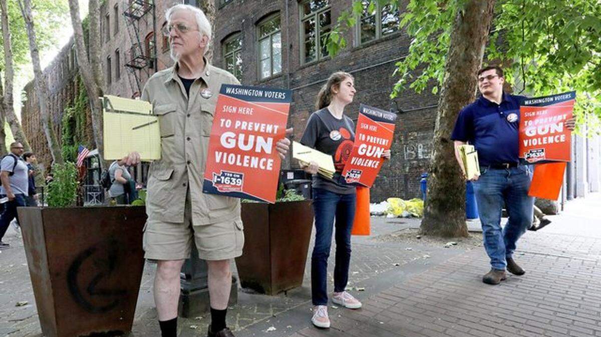 Supporters of Initiative 1639 assemble in Seattle’s Occidental Park to gather signatures. From left are Gus Webster of Seattle, Pavi Chance of Edmonds and, at far right, Jordan Waits of Tacoma.