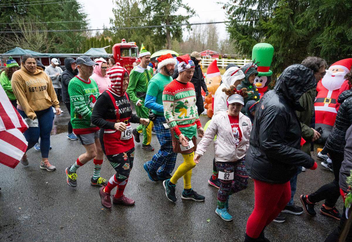Runners dressed in festive costumes and sweaters take off from the start line of the 5th Annual Christmas Eve Ugly Sweater 5K on the Nathan Chapman Memorial Trail in Puyallup, Wash. on Dec. 24, 2022. 