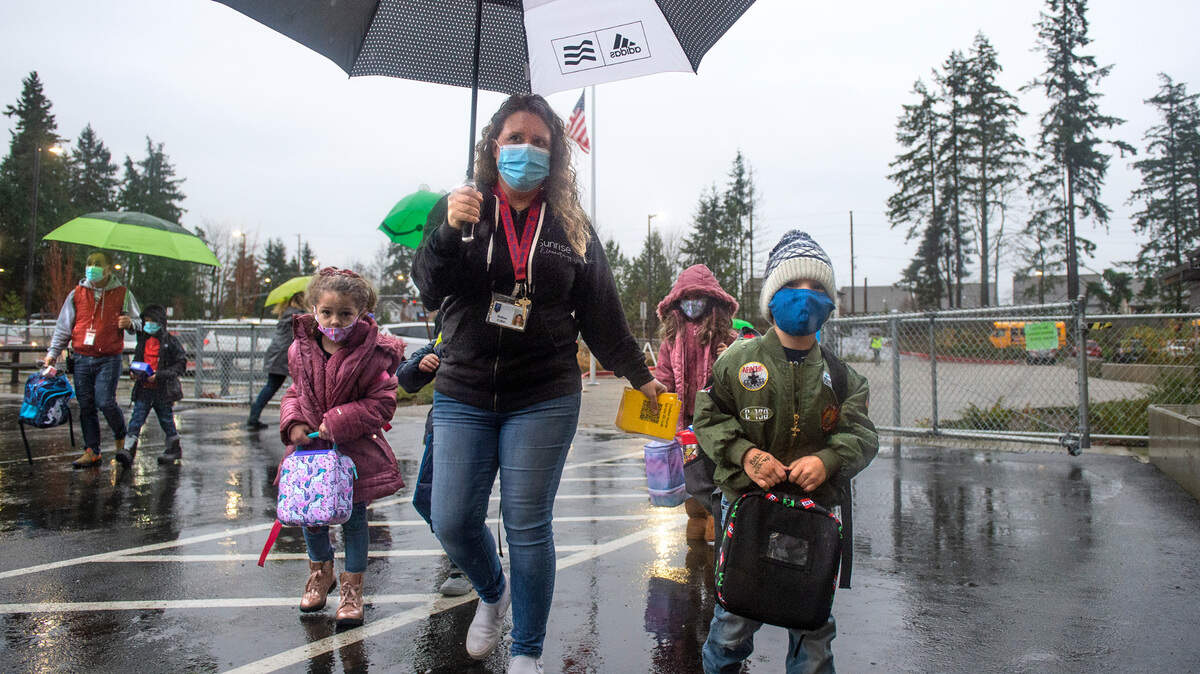 COVID coordinator Melissa McNamara escorts kindergarten and first-grade students as they arrive for the first day of modified in-person learning at Sunrise Elementary School in Puyallup on Tuesday, Jan. 12, 2021.
