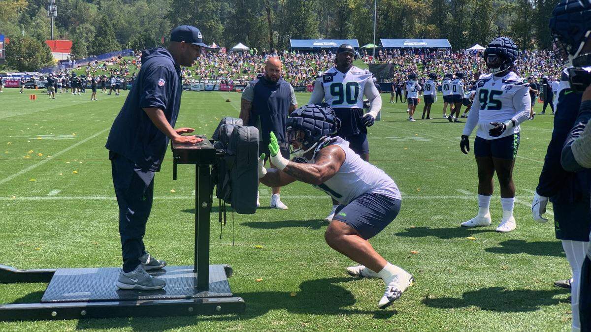 Rookie first-round NFL draft choice Byron Murphy getting coached by defensive coordinator Aden Durde during a sled drill at Seattle Seahawks training camp July 26, 2024, at the Virginia Mason Athletic Center in Renton. Fellow defensive linemen Jarran Reed (90) and Myles Adams (95) are watching before taking their turns.
