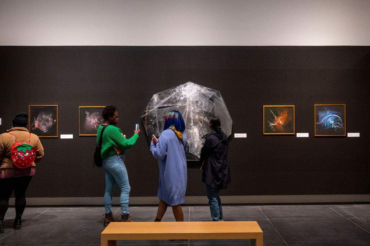 People look at an untitled acrylic on canvas piece (center) created by Camille Patha at her solo show at the Tacoma Art Museum on Thursday, March 2, 2023, in Tacoma, Wash.