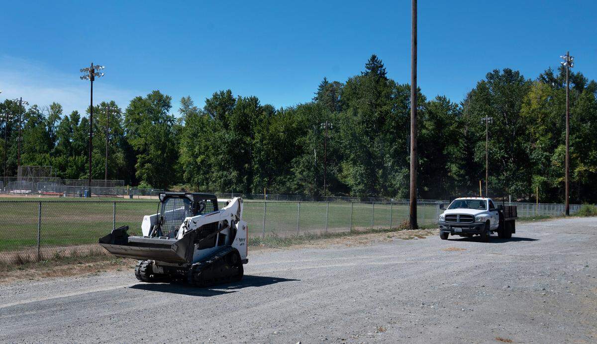 A work crew moves through the South End Recreation Area in Tacoma, Washington, on Wednesday, Aug. 16, 2023. The construction of a new fire station has been proposed for the wooded property (shown in background) on the northwest corner of the athletic complex.