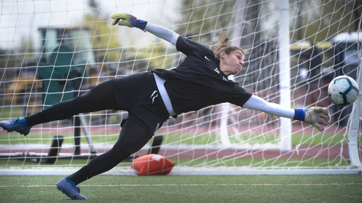 Reign goalkeeper Michelle Betos makes a diving deflection during soccer practice at Foss High School in Tacoma on Tuesday, April 9, 2019.