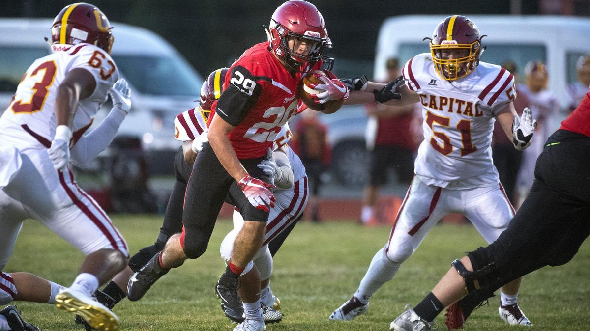 Yelm running back Carson Amendt breaks between Capital defensive ends Daniel Bailey (63) and Mason Bertelli during Friday night’s football game at Yelm High School on Sept. 28, 2018.