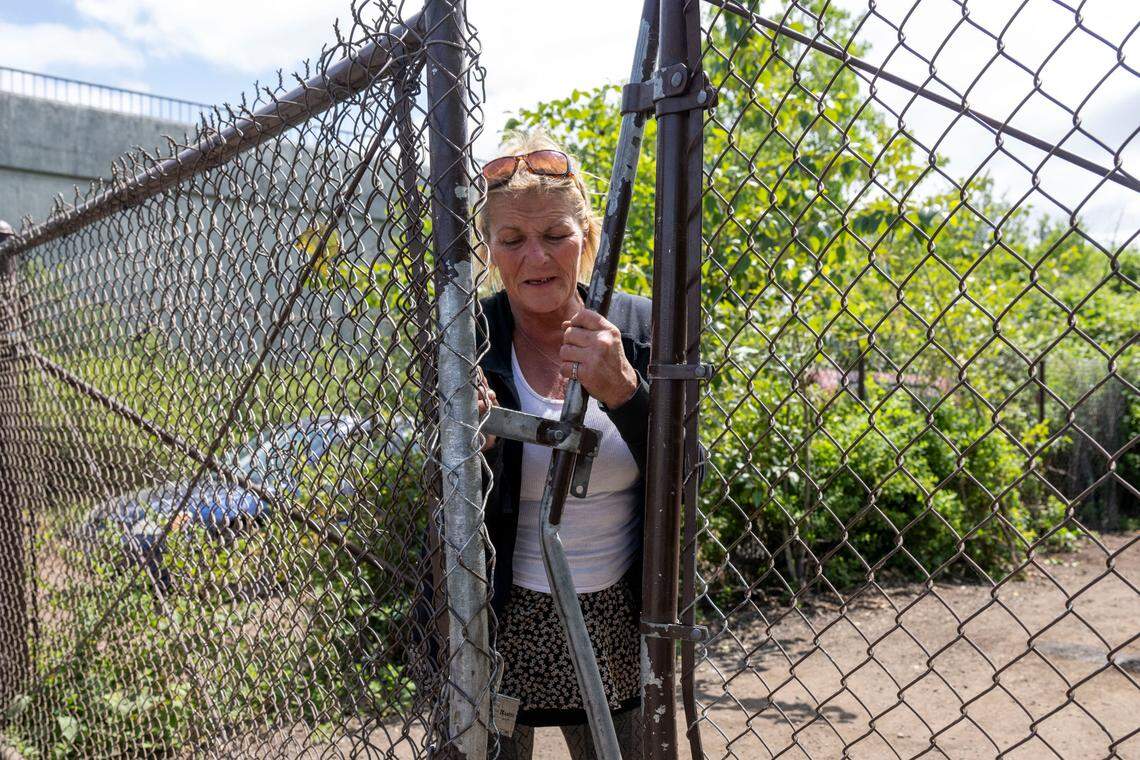 Michele Caldwell closes the gate to an encampment where she resides in her pickup truck along State Route 509 on Tuesday, May 30, 2023, in Tacoma, Wash. Caldwell, who said she was an engineer at Boeing and a special education teacher, could not believe this is where she ended up at the age of 56. The Greater Lakes Homeless Outreach and Stabilization Team visited her that day to provide food, health care and supplies to whoever needed help.