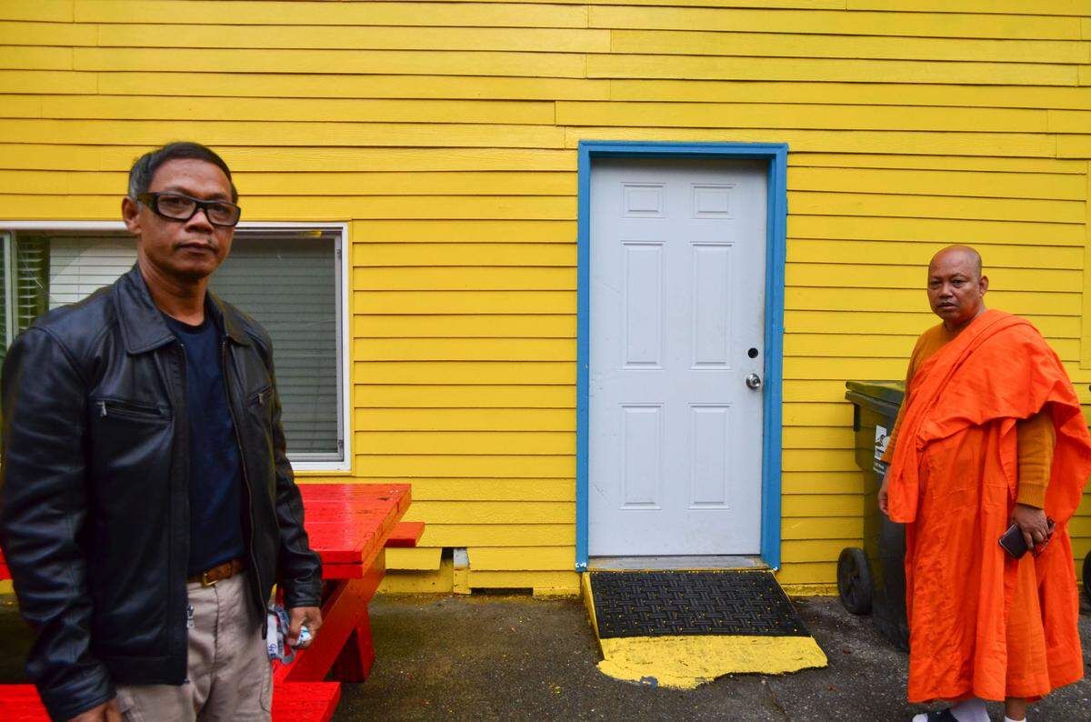 Chea Poeuv, head monk of Khmer Theravadin Buddhist Temple and Hoeurn Mon, assistant head monk, pose in front of a door to the basement of the temple where squatters have stayed for months.